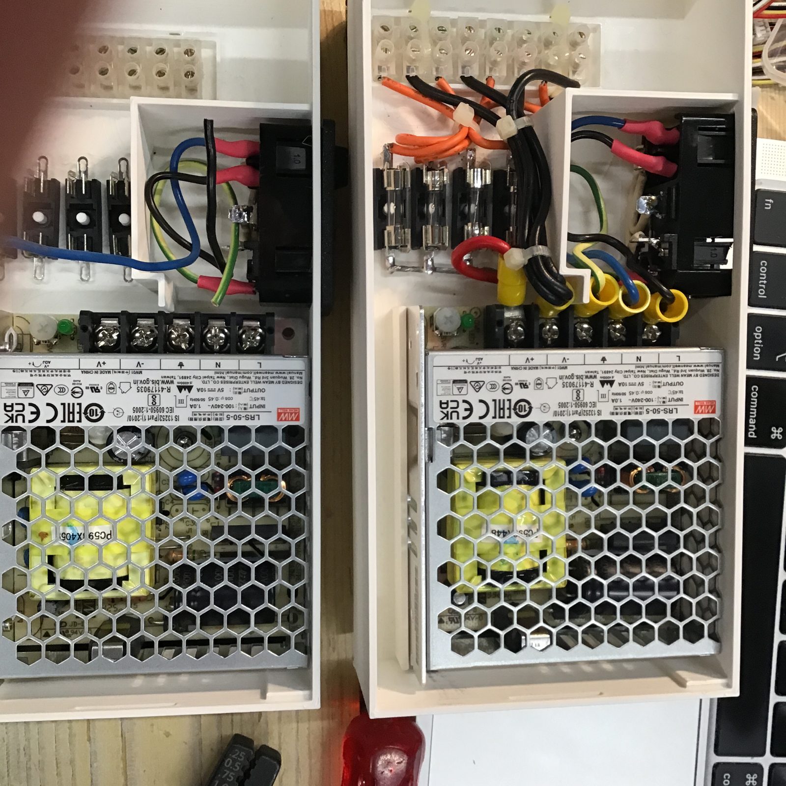 Twee voedingskasten in aanbouw. Rechts helemaal bedraad: de netaansluiting achter de scheidingswand, de vier zekeringen en de draden naar de kroonsteen.